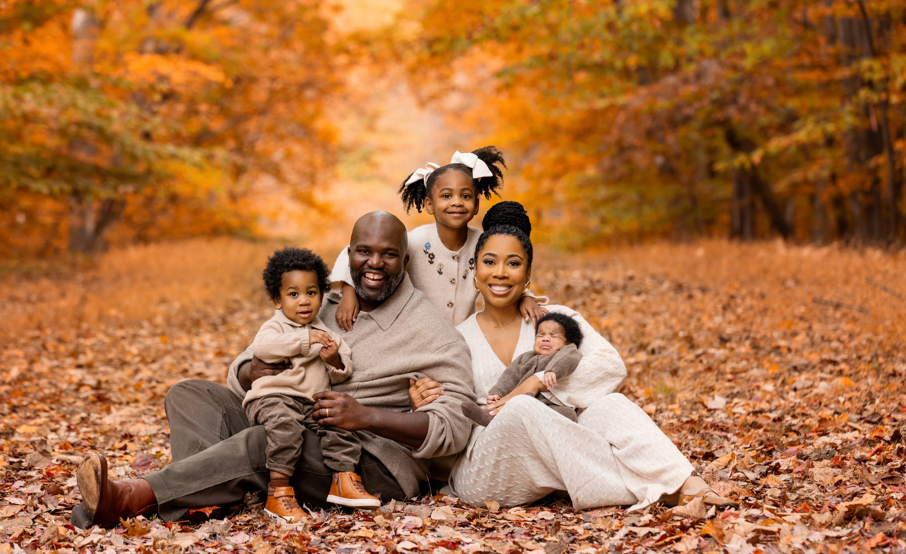 A family sitting together among fallen autumn leaves at Black Hill Regional Park